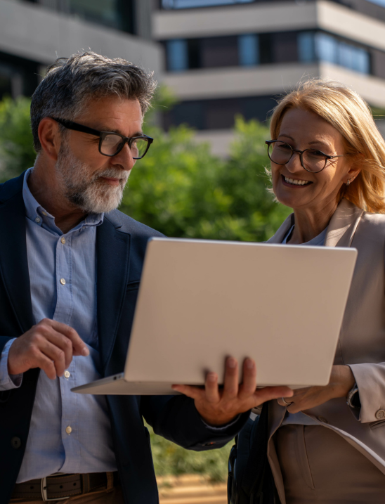 Image of two property managers, smiling and looking on a laptop, focusing on linking performance to compliance.